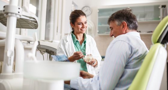 Female dentist in dental office talking with senior male  patient and preparing for treatment.; Shutterstock ID 573797008
